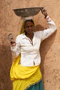 JAIPUR, RAJASTHAN, INDIA - JULY 30, 2008: Female laborers transporting water and plaster in bowls carried on the head during the restoration of a palace inside Amber Fort in Jaipur, Rajasthan, India.
