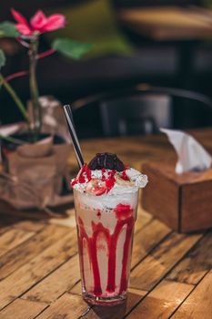 A glass with delicious coffee ice cream red shake on the wooden background.