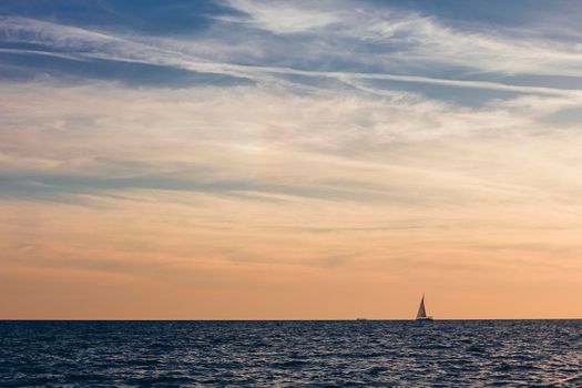 A beautiful sky with a boat in the sea with clouds over.