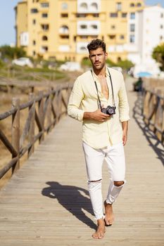 Handsome man photographing in a coastal area with an SLR camera