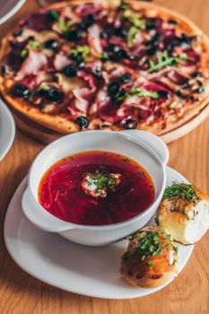 Ukrainian and russian national red borsch with buns and other dishes served on the table.