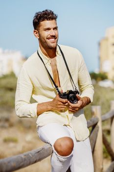 Smiling man photographing in a coastal area with an SLR camera