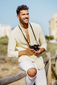 Smiling man photographing in a coastal area with an SLR camera