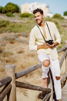 Smiling man photographing in a coastal area with an SLR camera