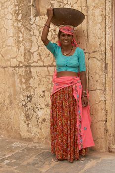 JAIPUR, RAJASTHAN, INDIA - JULY 30, 2008: Female laborers transporting water and plaster in bowls carried on the head during the restoration of a palace inside Amber Fort in Jaipur, Rajasthan, India.