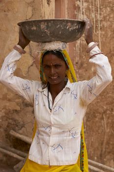 JAIPUR, RAJASTHAN, INDIA - JULY 30, 2008: Female laborers transporting water and plaster in bowls carried on the head during the restoration of a palace inside Amber Fort in Jaipur, Rajasthan, India.