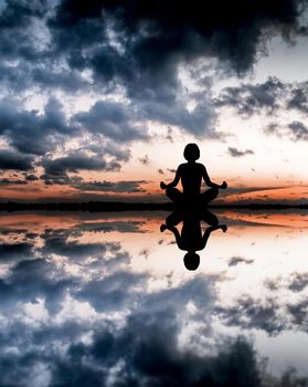 Sunset yoga woman on sea coast.