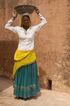 JAIPUR, RAJASTHAN, INDIA - JULY 30, 2008: Female laborers transporting water and plaster in bowls carried on the head during the restoration of a palace inside Amber Fort in Jaipur, Rajasthan, India.