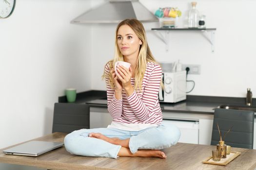 Young caucasian woman holding a cup of coffee at home.