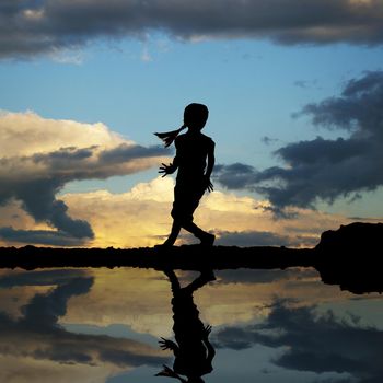 silhouette of a little girl dancing on a background of the sea