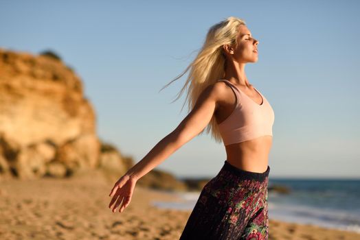 Woman enjoying the sunset on a beautiful beach in Cadiz, Andalusia, Spain. Young female opening arms and breathing the sea air.