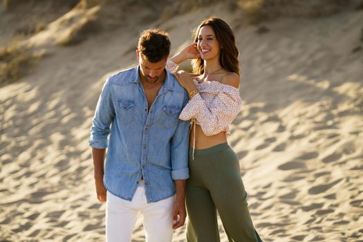 Young couple standing on the sand of the beach wearing casual clothes.