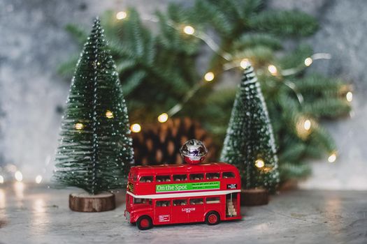 Toy double decker bus and fir tree with Christmas lights. New Year travel concept