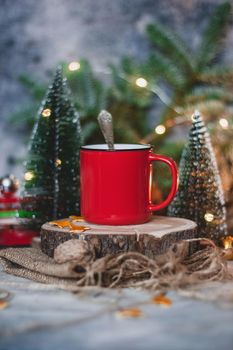Cozy winter drink hot chocolate cocoa in red mug with fir tree, candles and Christmas lights