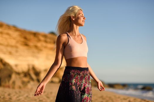 Woman enjoying the sunset on a beautiful beach in Cadiz, Andalusia, Spain. Young female opening arms and breathing the sea air.