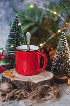 Cozy winter drink hot chocolate cocoa in red mug with fir tree, candles and Christmas lights