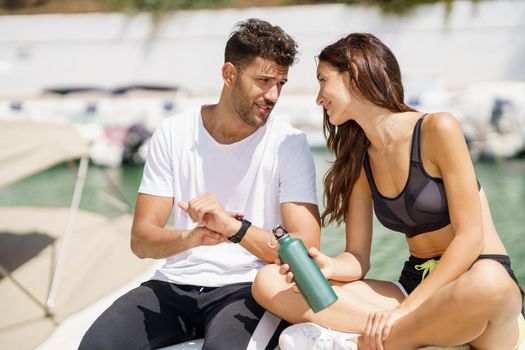 Man showing his marks to an athletic woman on a sports watch after exercise. People using smartwatch.