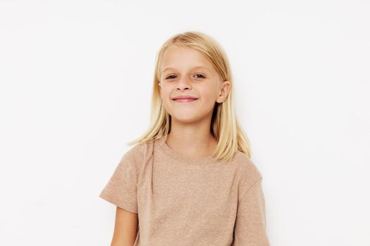 Positive little girl in a beige t-shirt on a light background. High quality photo