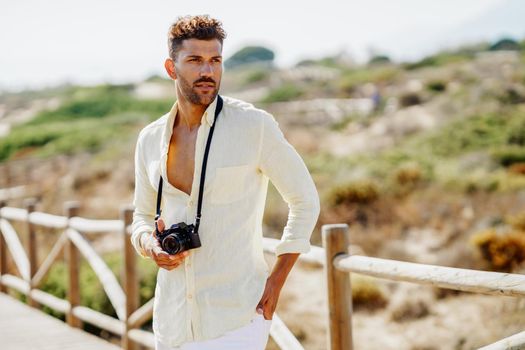 Handsome man photographing in a coastal area with an SLR camera