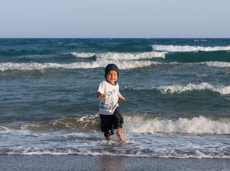 LIMASSOL, CYPRUS, Jun 19, 2010: A little boy walks for the first time along the seashore enjoying the fresh air and sea waves