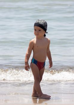 A little boy for the first time on the seashore enjoying the fresh air and sea waves