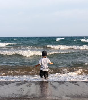 LIMASSOL, CYPRUS, Jun 19, 2010: A little boy walks for the first time along the seashore enjoying the fresh air and sea waves
