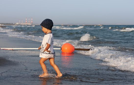 LIMASSOL, CYPRUS, Jun 19, 2010: A little boy walks for the first time along the seashore enjoying the fresh air and sea waves