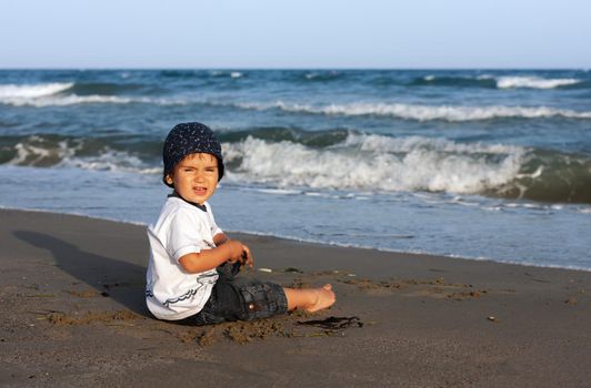 LIMASSOL, CYPRUS, Jun 19, 2010: A little boy sits for the first time on the seashore enjoying the fresh air and sea waves