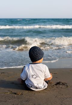 LIMASSOL, CYPRUS, Jun 19, 2010: A little boy sits for the first time on the seashore enjoying the fresh air and sea waves