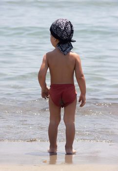 A little boy for the first time on the seashore enjoying the fresh air and sea waves