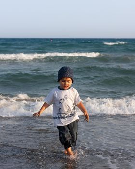 LIMASSOL, CYPRUS, Jun 19, 2010: A little boy walks for the first time along the seashore enjoying the fresh air and sea waves