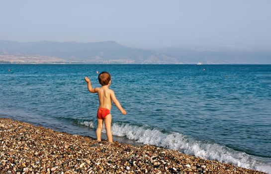 Healthy lifestyle. A little boy walks and plays on the seashore.