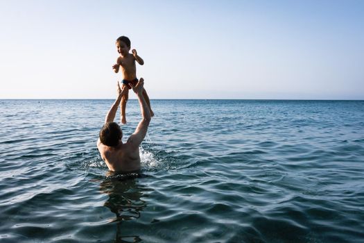 Happy family and healthy lifestyle. A young father teaches a child to swim in the sea
