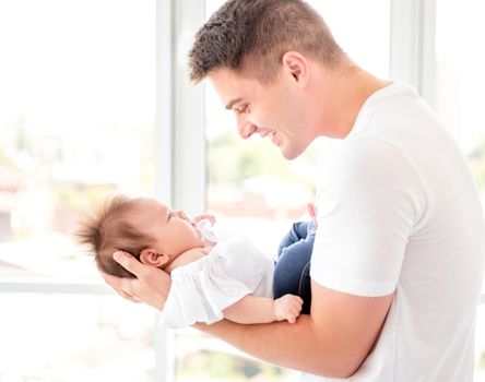 Father embracing infant near window