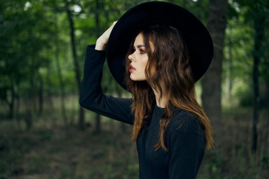 woman witch in black hat in the forest posing fantasy. High quality photo