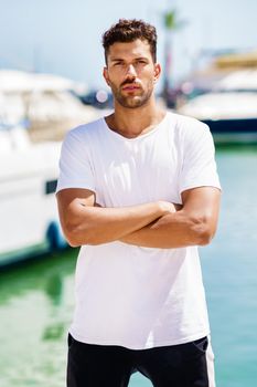 Fitness man, model of fashion, in sportswear outfit posing on waterfront harbour.