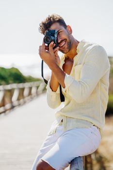 Handsome man photographing in a coastal area with an SLR camera