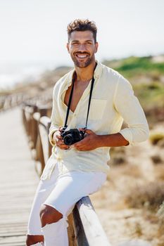 Smiling man photographing in a coastal area with an SLR camera