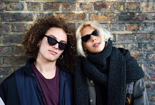 Young couple enjoying Camden town in front of a brick wall typical of London, UK