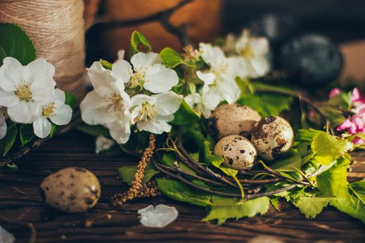 Easter eggs in the nest on rustic wooden background with apple blossom branch