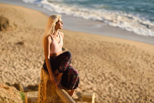 Woman enjoying the sunset on a beautiful beach in Cadiz, Andalusia, Spain. Young female sitting on beautiful stairs looking at the sea with golden light.