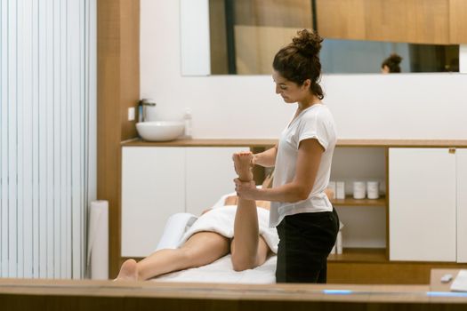 Middle-aged woman having a leg massage in a beauty salon. Body care treatment in a beauty centre.