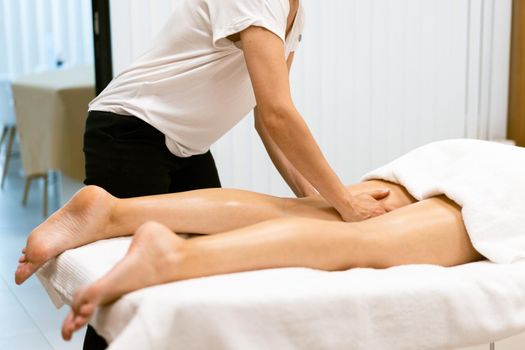 Middle-aged woman having a leg massage in a beauty salon. Body care treatment in a beauty centre.