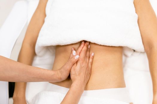 Middle-aged woman having a belly massage in a beauty salon. Body care treatment in a beauty centre.