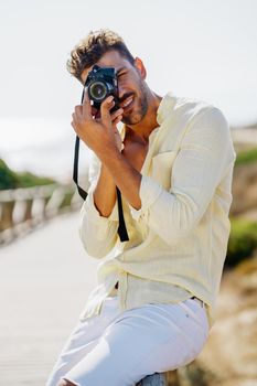 Handsome man photographing in a coastal area with an SLR camera
