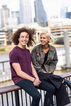 Happy couple talking sitting near River Thames, London. UK