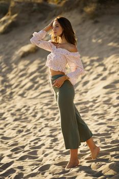 Young beautiful woman standing on the sand of the beach wearing casual clothes.