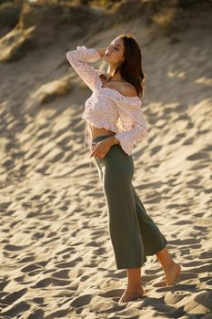 Young beautiful woman standing on the sand of the beach wearing casual clothes.