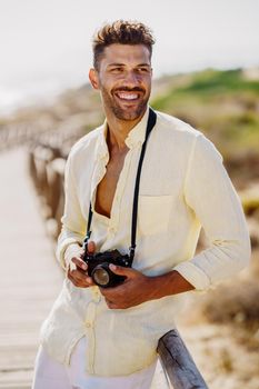 Smiling man photographing in a coastal area with an SLR camera