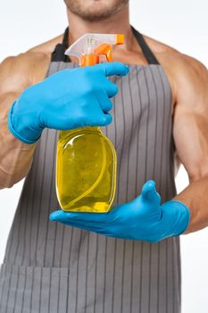 man in apron detergent cleaning service light background. High quality photo